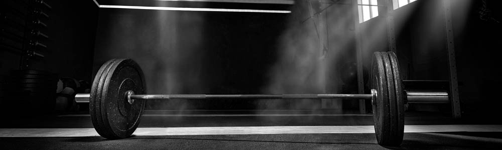 Black & white photo of a barbell laying on a gym floor